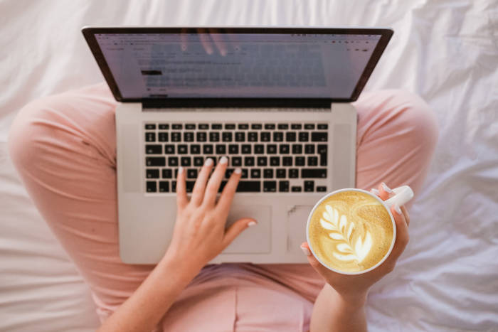 woman holding a cup of coffee and using Our-Venue.com on a laptop