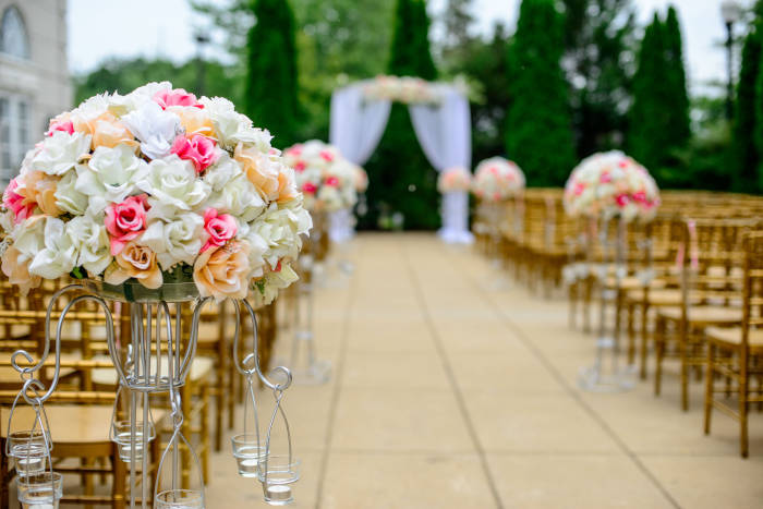 An outside ceremony setup, with floral arrangements along the aisle